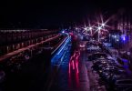 Strasse einer Großstadt bei Nacht mit roten blauen Lichtern der Autos und Parkplätze links und rechts