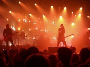 Rockkonzert: Disco voller Leute die auf den Sänger mit Gitarre under Gelb-orangen Lichtern steht