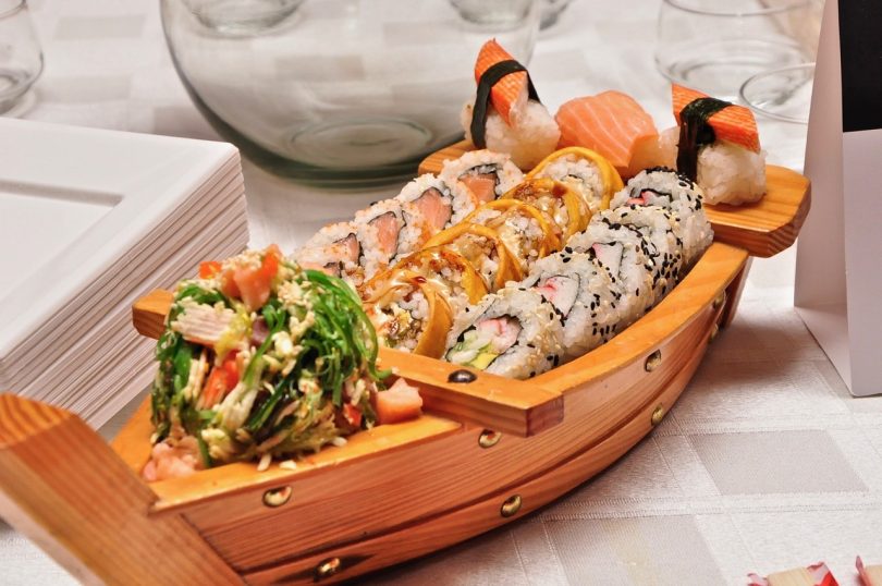Kleines Holzschiff mit verschiedenen Sorten von Sushi darin
