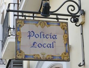 antikes Straßenschild aus Porzellan in blau eins und gelb mit der Aufschrift Bolivia local und dem Wappen der Lokalpolizei