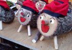 auf einem Holzbrett sind verschieden große cagatios aufgestellt, alle mit rotem offenem Mund und der traditionellen roten Mütze mit schwarzen Streifen