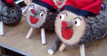 auf einem Holzbrett sind verschieden große cagatios aufgestellt, alle mit rotem offenem Mund und der traditionellen roten Mütze mit schwarzen Streifen