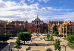 Vorderansicht der modernistischen Anlage des Krankenhauses San Pau in Barcelona, Gebäude in roten färben und ein kleiner Park davor