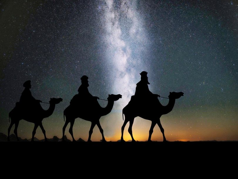 in der Wüste sind drei Kamele mit drei Männern zu sehen wie sie durch die nacht ziehen, vermutlich die heiligen drei Könige