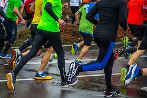 eine nasse Straße und mehrere Marathonläufer in Turnschuhen und Loggins und kurzen Hosen