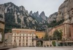 im Hintergrund das Felsengebirge von Montserrat und im Vordergrund Hausblöcke in rot und orange Tönen