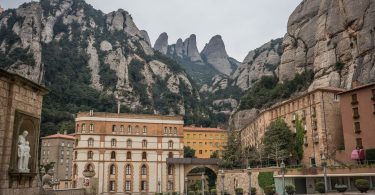 im Hintergrund das Felsengebirge von Montserrat und im Vordergrund Hausblöcke in rot und orange Tönen