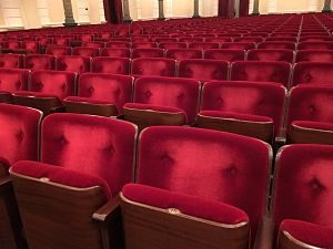 mehrere aufklappbare Sessel eines Theaters die mit einem rotem Samtstoff bezogen sind