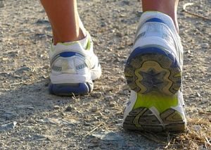 Die Turnschuhe eines Joggers oder einer Joggerin, weiss mit blauen Details