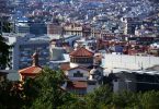 Blick auf Barcelona vom Gaudi Park aus, im Vordergrund grüne Bäume und danach Gebäude so weit das Auge reicht