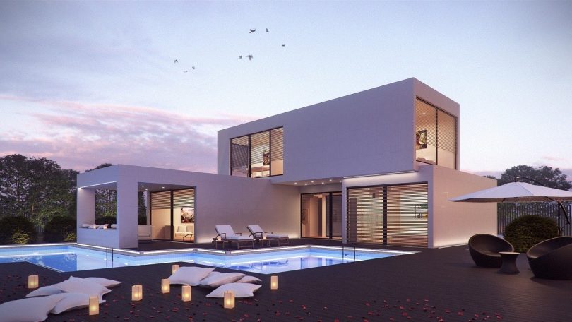 ein zweistöckiges fertigbauhaus in viereckigen formen mit einer überdachten Terrasse und einem Schwimmbad davor