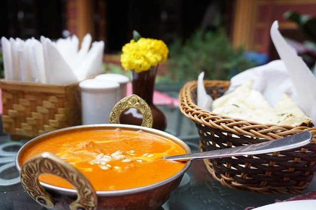 tics auf einer Terrasse eines indischen Restaurants mit einem Brotkorb, gelben Blumen salz und Pfeffer und einer typisch indischen Schüssel mit curry