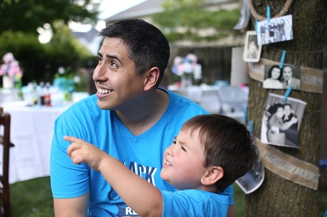 Vater und Sohn im blauen T-Shirt der vater lächelt und schaut in die Richtung in die der junge mit dem Finger zeigt