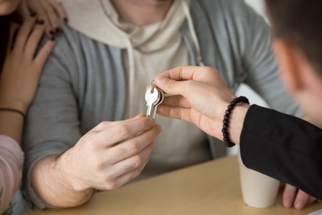 ein Immobilienmarkler übergibt gerade die Wohnungsschlüssel der neuen Mieterin