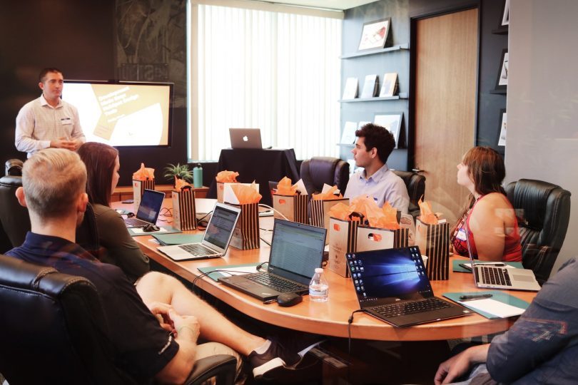 in einem Konferenzraum sitzen sechs sommerlich gekleidete Personen mit ihren Laptops
